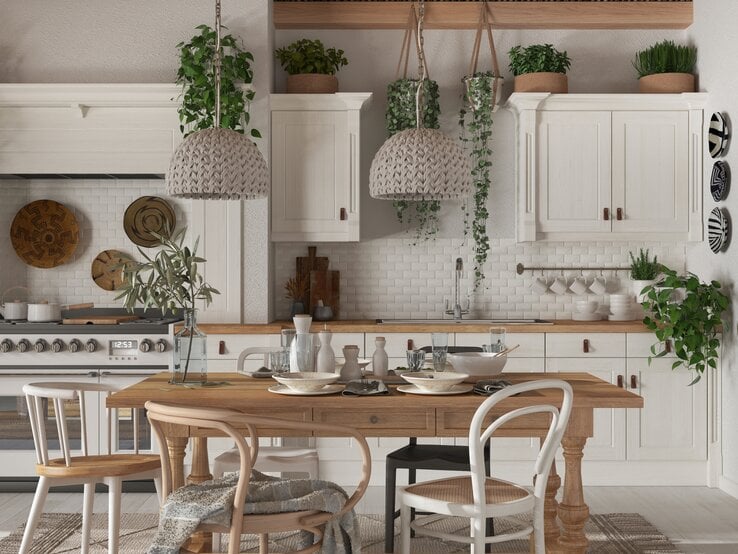 Eine weiße Küche mit Esstisch und vielen Zimmerpflanzen.
