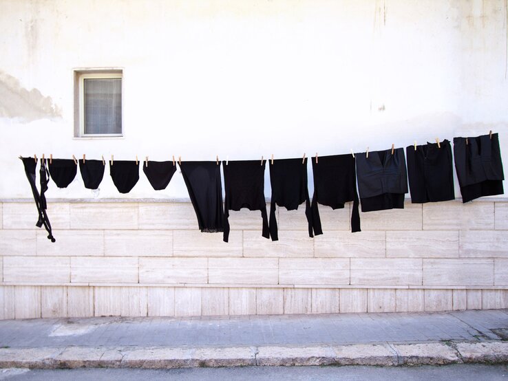 Schwarze Kleidung hängt an einer Leine in der Sonne | © iStock/JannHuizenga