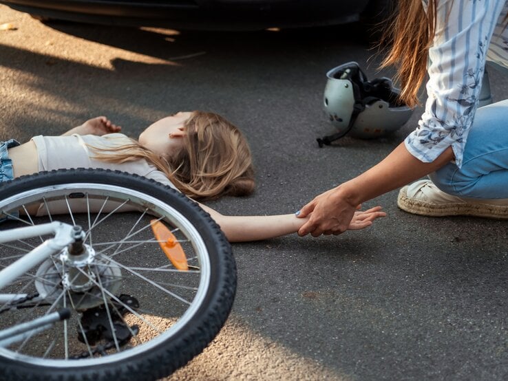 Mädchen liegt verletzt auf der Straße nach Unfall. | © Getty Images/ D-Keine 