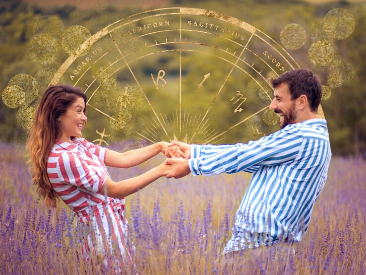 Ein fröhliches Paar hält sich an den Händen und dreht sich auf einem lila blühenden Lavendelfeld. Sie lachen und blicken einander liebevoll an. Über ihnen schwebt ein transparentes astrologisches Diagramm mit goldenen Symbolen und Linien, das die Tierkreiszeichen von Wassermann bis Skorpion zeigt. Glitzernde Bokeh-Lichteffekte umgeben sie und verleihen dem Bild eine traumhafte Atmosphäre. Die Frau trägt ein gestreiftes Kleid in Rot und Weiß, der Mann ein blau-weiß gestreiftes Hemd. Beide scheinen in einem Moment purer Freude und Verbindung gefangen zu sein.