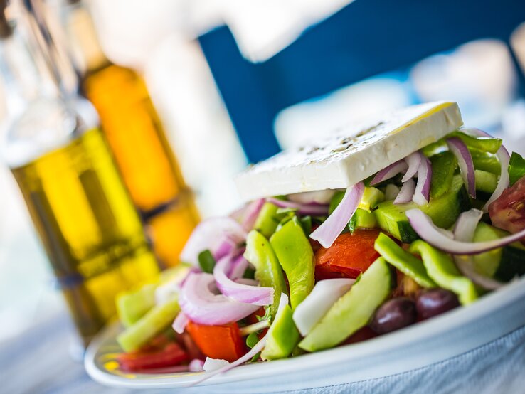 Ein mit Feta garnierter griechischer Salat auf einem Teller. 