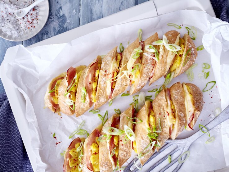 Hasselback-Baguette Hawaii auf einem Backblech mit weißem Backpapier.