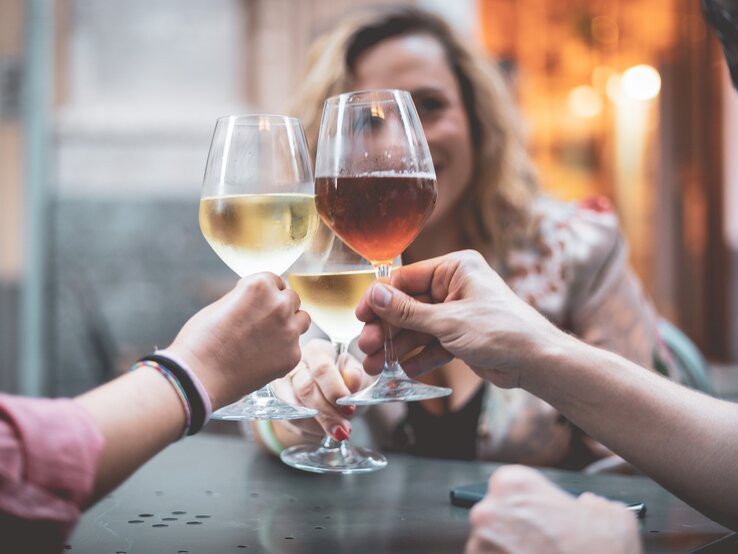 Ist Wein vegan: drei Freunde stoßen mit Wein an.