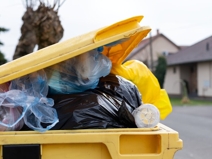 Eine überquellende Mülltonne auf der Straße in einem Wohngebiet. | © iStock / Ocskaymark