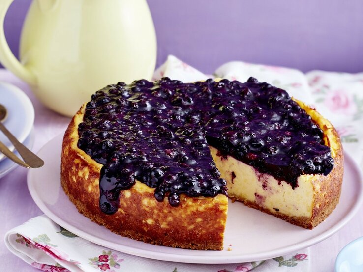 Auf einem Teller steht ein Heidelbeer-Pudding-Kuchen. Er ist sehr cremig und mit Heidelkompott bedeckt.