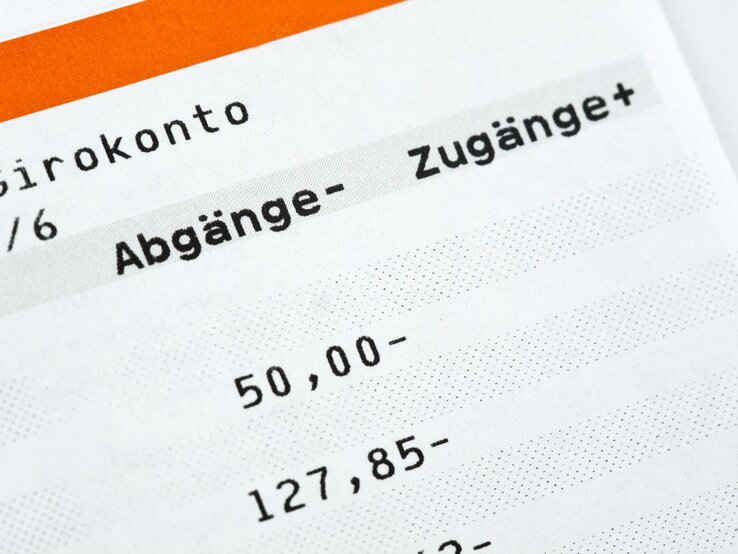 Ausschnitt eines Kontoauszugs mit dem Titel "Girokonto", unterteilt in die Kategorien "Abgänge -" und "Zugänge +", mit zwei aufgelisteten Beträgen: "50,00-" und "127,85-".