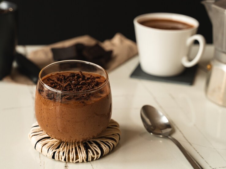 Ein Glas mit Schoko-Espresso-Mousse auf einem weißen Tisch.