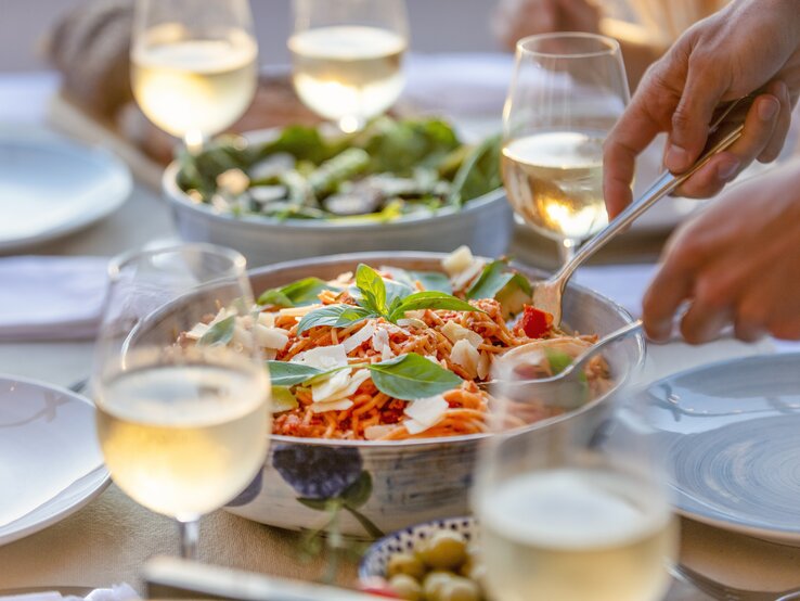 Nudelsalat Silberfarbene Schüssel gefüllt mit Spaghett-Salat umrundet von Weingläsern.