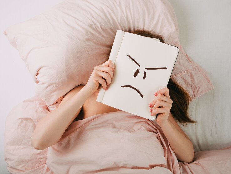 Frau im Bett mit schlechter Laune
