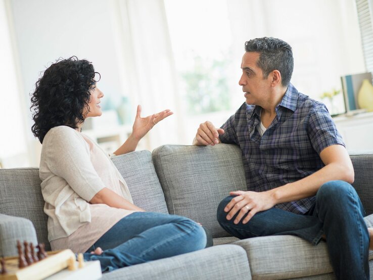 Paar sitzt auf dem Sofa und diskutiert | © Getty Images / Tetra Images