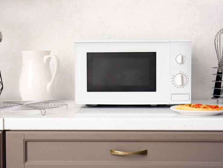 Eine Mikrowelle steht auf einer Küchenzeile.