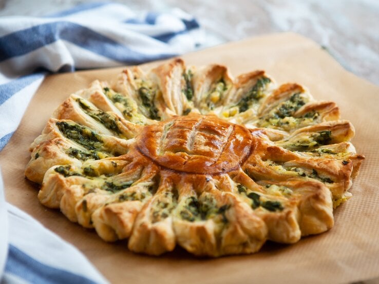 Zupfbrot-Sonne mit Spinat und Feta auf einem Holzbrett. 