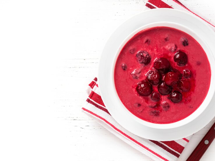 Sauerkirschsuppe Ein weißer Teller mit der roten Suppe auf rot-weißem Tuch und weißem Tisch. Alles direkt von oben fotografiert.