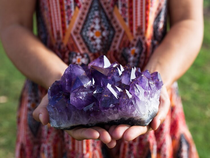 Eine Frau hält einen großen Amethyst in der Hand. 