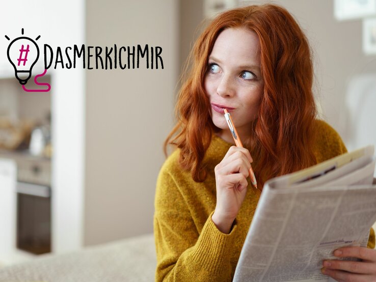 Eine Frau mit rotem Haar und einem senfgelben Pullover liest nachdenklich eine Zeitung und hält dabei einen Stift an ihre Lippen. Ihr Blick ist nachdenklich und reflektierend, als würde sie über das Gelesene nachdenken oder eine Pause machen, um ihre Gedanken zu sammeln. Neben ihrem Kopf ist der Hashtag "#DAS MERK ICH MIR" neben einer stilisierten Glühbirnen-Grafik zu sehen, was darauf hindeutet, dass sie gerade eine Idee oder einen wichtigen Punkt zum Merken gefunden hat. 