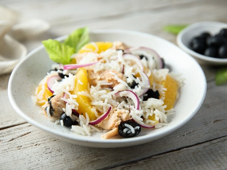 Reissalat mit Thunfisch und Mandarine auf weißem Teller. 
