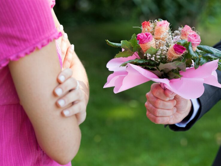 Mann überreicht Frau Blumenstrauß, von beiden Personen sind nur die Hände zu sehen