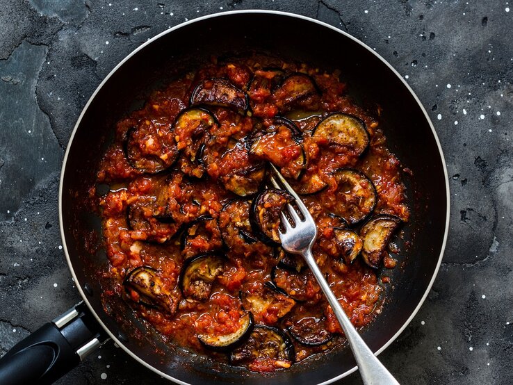 Eine schwarze Pfanne auf dunklem Steinuntergrund mit der Auberginenpfanne.