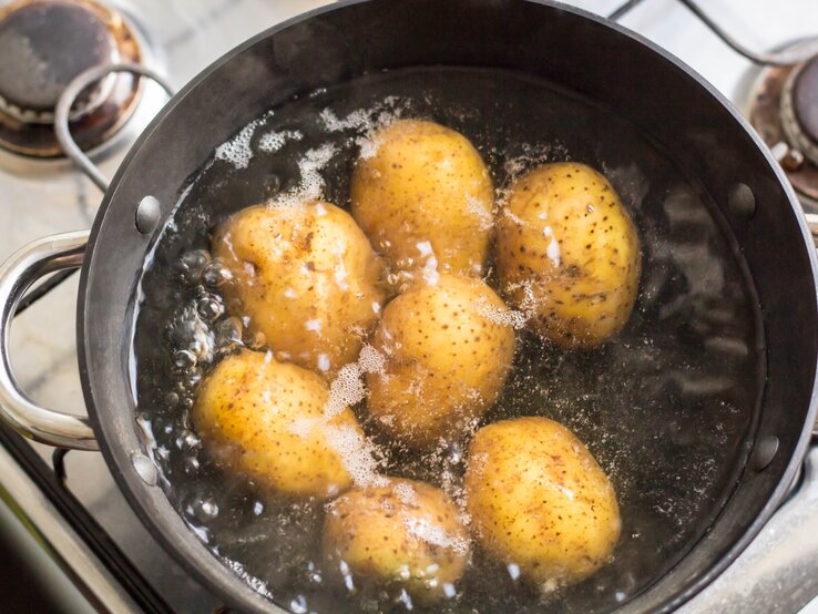 Ein Kochtopf mit kochendem Wasser und Kartoffeln.