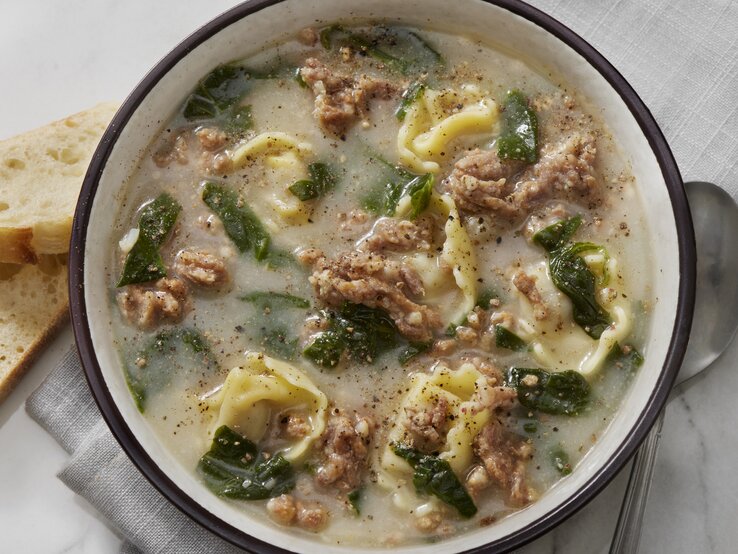 Suppenschüssel gefüllt mit einer cremigen Suppe mit Tortellini und Hackfleisch. 