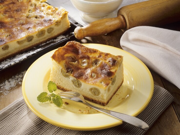 Ein gelber Teller mit einem Stück Schmandkuchen auf einem rustikalen Holztisch von schräg oben fotografiert.