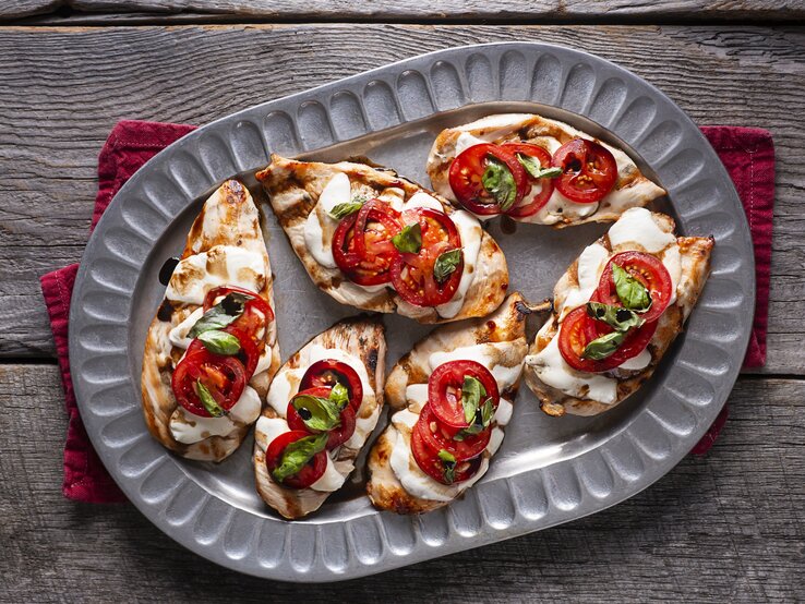 Hähnchen überbacken mit Tomate und Mozzarella auf Servierteller.