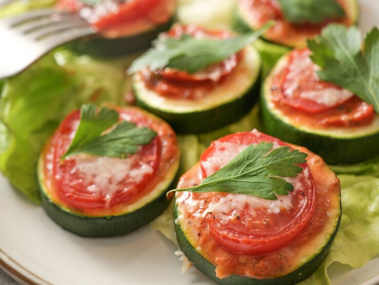 Zucchini-Bruschetta-Häppchen auf einem Teller, daneben eine Gabel.
