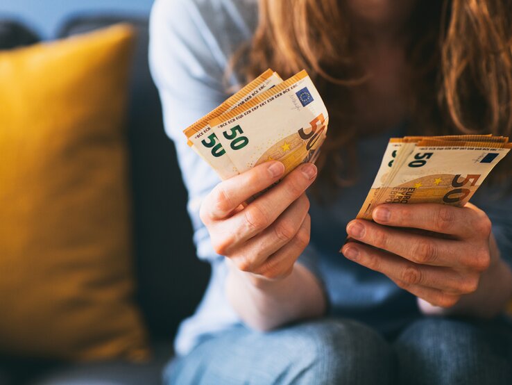 Rothaarige Frau hat mehrere Geldscheine in der Hand.