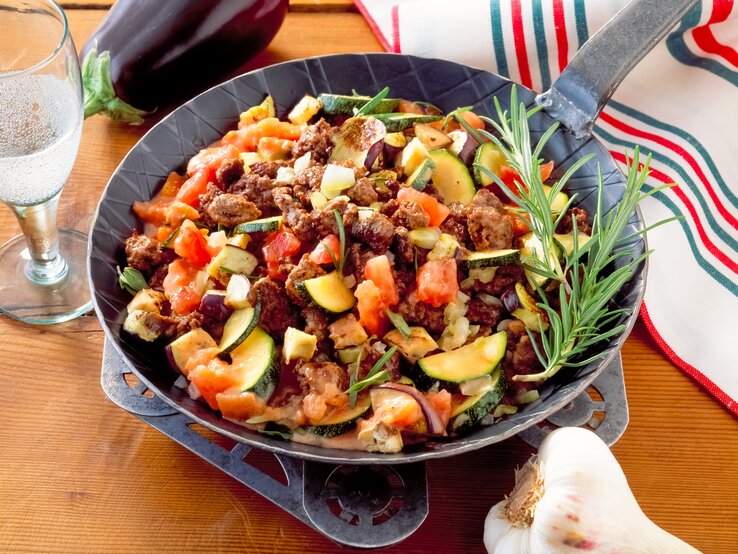 Zucchini-Hackfleisch-Pfanne mit Tomaten auf Holztisch. 