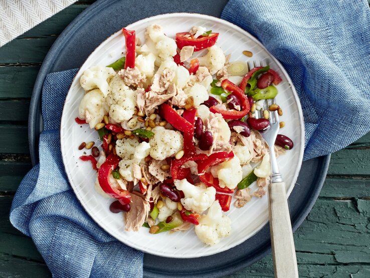 In einer Schüssel ist eine Blumenkohl-Thunfisch-Bowl angerichtet. Sie ist mit Bohnen und Paprika verfeinert.