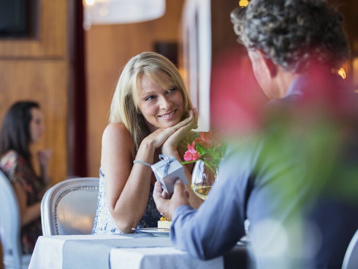 Ein Mann überreicht einer überraschten Frau in einem Cafe ein Geschenk | © imago/Science Photo Library