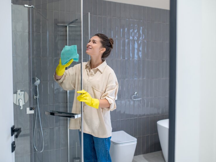 Eine junge Frau reinigt Ihre Dusche.