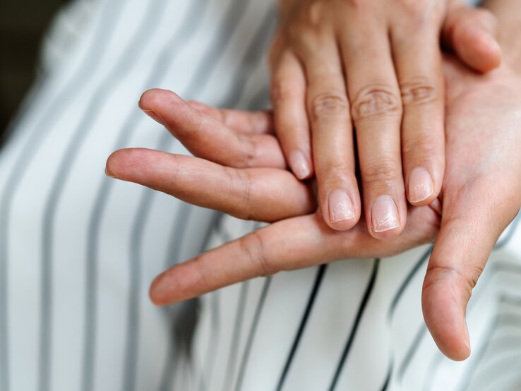 Eine Person präsentiert ihre Fingernägel.