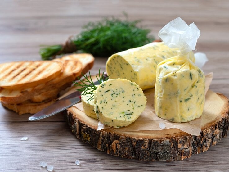Kräuterbutter selbst machen: Mit einer Dill-Zitronenbutter schmeckt sogar Fleisch! Eine Rolle mit Dill-Zitronenbutter auf einer Baumscheibe.