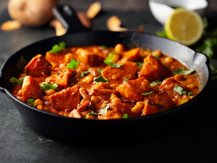 Eine dunkle Pfanne mit Tikka Masala mit Süßkartoffeln und Kichererbsen bestreut mit frischem Koriander.