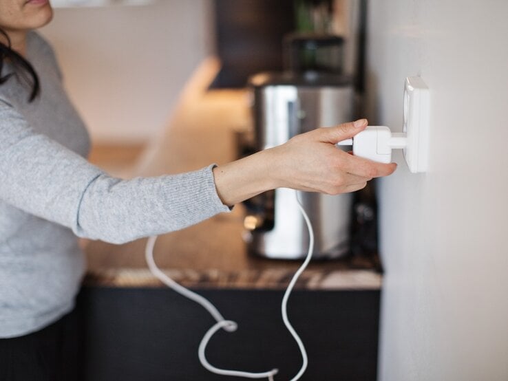 Eine Frau steckt einen Stecker in eine Steckdose.