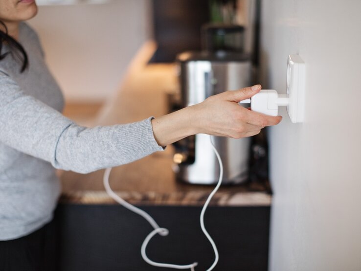 stecker_ziehen_haushaltsgeraete Eine Frau steckt einen Stecker in eine Steckdose.