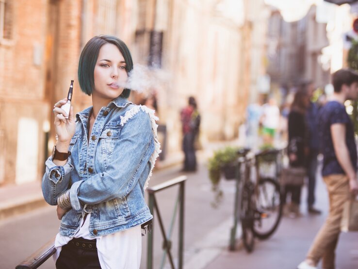 Eine Frau raucht auf der Straße eine E-Zigarette.