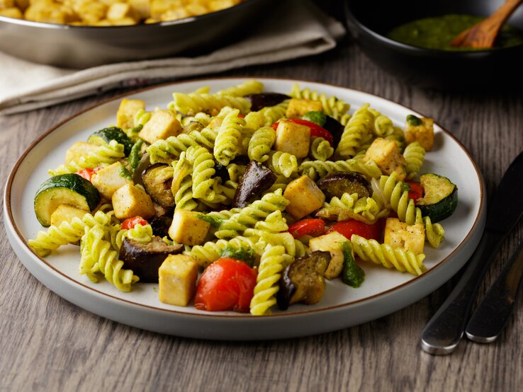 Pasta mit Pesto, gegrilltem Gemüse und Tofu auf weißem Teller