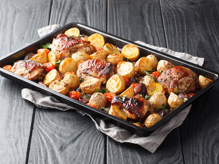 Balsamico-Hähnchen mit Kartoffeln auf Backblech auf dunklem Holz.