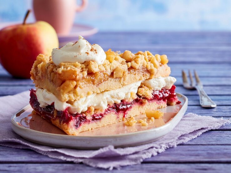 Auf einem Teller steht ein Stück Prasselkuchen mit Vanille-Mascarpone-Creme. Es ist mit einem Tuff Creme verfeinert.