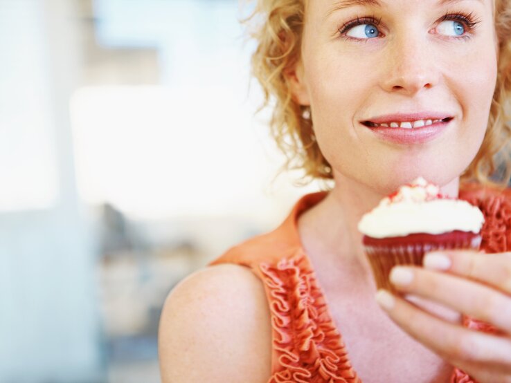 Frau die genüsslich einen Cupcake betrachtet.