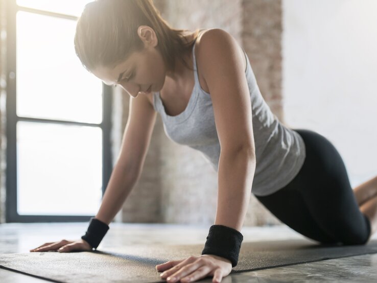 Liegestütze – auch die vereinfachte Version auf den Knien – sind ein tolles Training für die Brustmuskulatur. Einfache Übungen können schon dabei unterstützen, die Brust zu straffen – auch wenn das Bindegewebe nachgibt. Eine Frau macht Liegestütze, um ihre Brüste zu straffen.