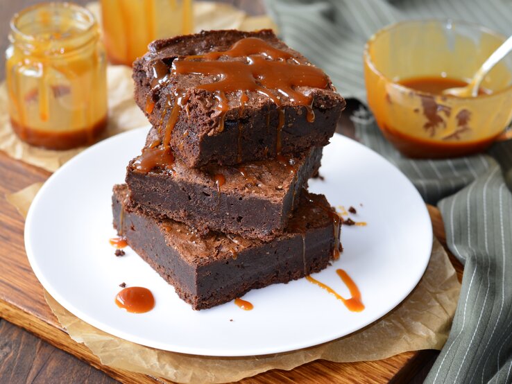 Ein Teller mit Salzkaramell-Brownies auf einem Holzbrett.