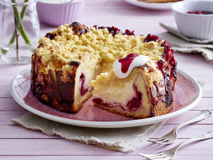 Kirsch-Vanillekuchen mit Streuseln auf Teller serviert.