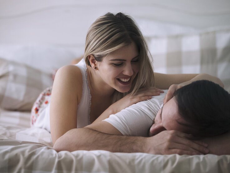 junges Paar liegt zusammen im Bett, sie streichelt ihn | © iStock/nd3000