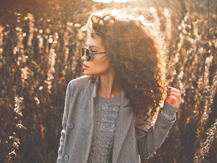 Frau mit schönen, definierten Locken steht auf einem Feld. 