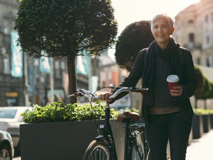 Frau mit Kaffee auf Fahrrad