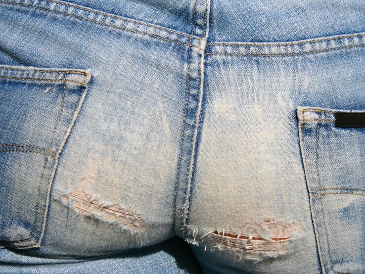 Eine Jeans von hinten, die am Gesäß gerissen ist
