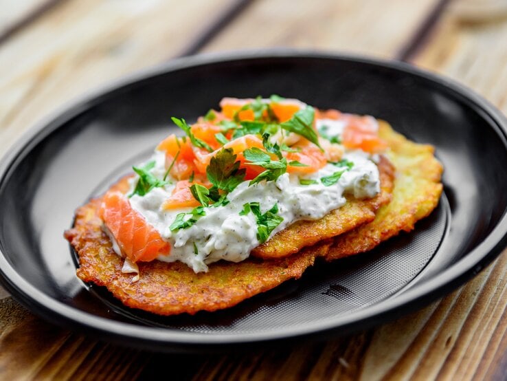 Gebratener Kartoffelpuffer mit Quark und einer Scheibe Räucherlachs belegt. 